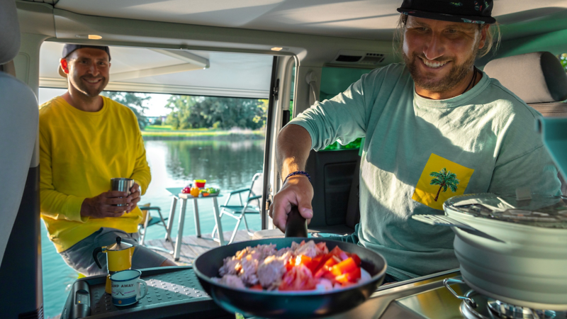 Ein Mann Kocht in der Campingküche des VW California.