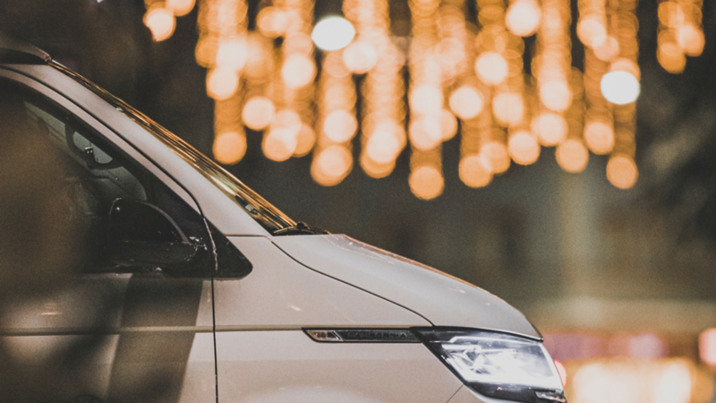 Nahaufnahme eines VW California im Profil, im Hintergrund glitzernde, verschwommene Lichter.