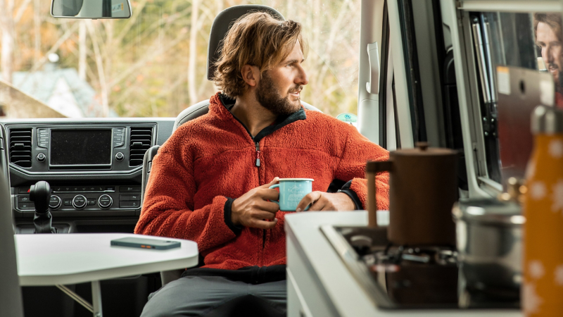 En man dricker kaffe i en VW California.