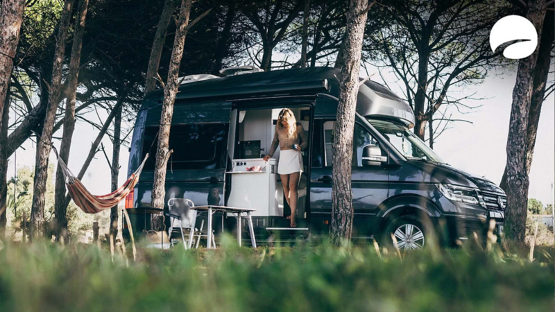 Photo of a woman standing in the side door of a parked Grand California. 