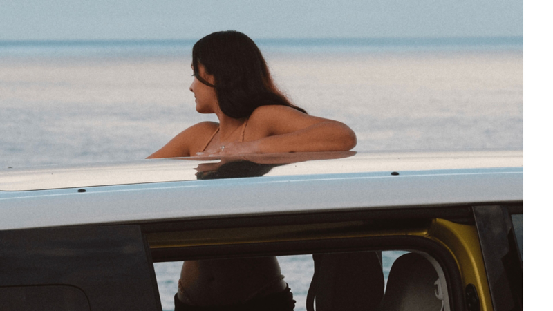 Woman looking out to ocean on VW van