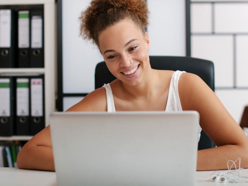 Smiling woman sitting at a desk and looking at her laptop