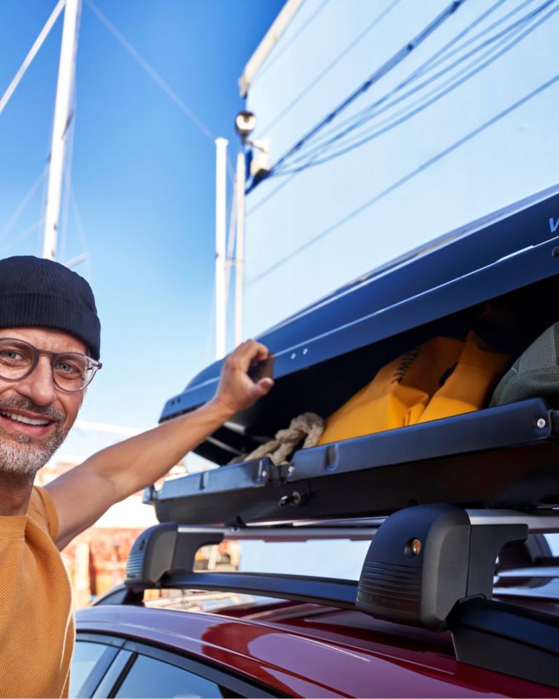 Une homme ouvre son coffre de toit d'Origine Volkswagen - Accessoires spécifiques aux modèles