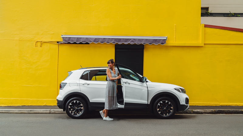 Side view of VW car with a woman opening the car door 