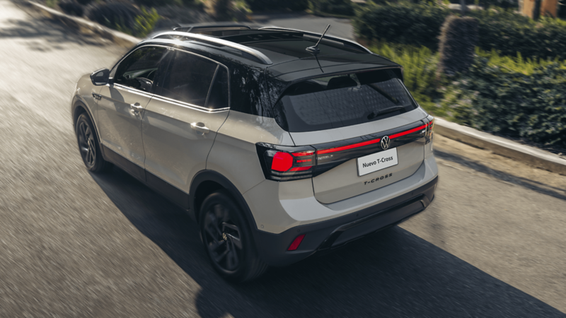 Volkswagen T-Cross blanco en movimiento, vista trasera con franja LED y diseño renovado