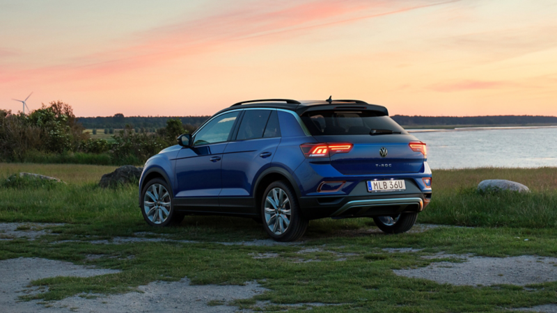 En blå Volkswagen T-Roc sedd snett bakifrån med havet i bakgrunden