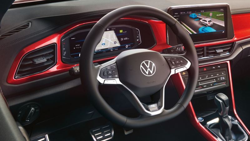 View of the cockpit of the red T-Roc Cabriolet with the multifunction steering wheel, radio and digital cockpit.