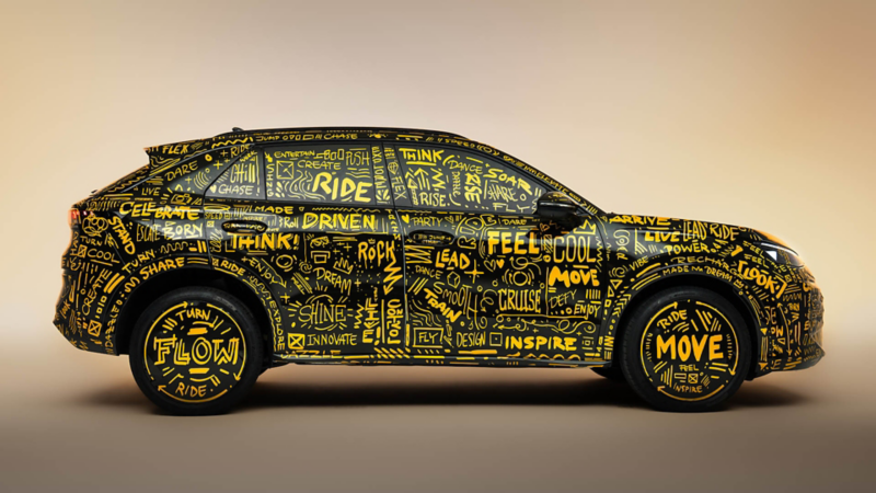 a side view of a black T-Roc covered in yellow graffiti writing