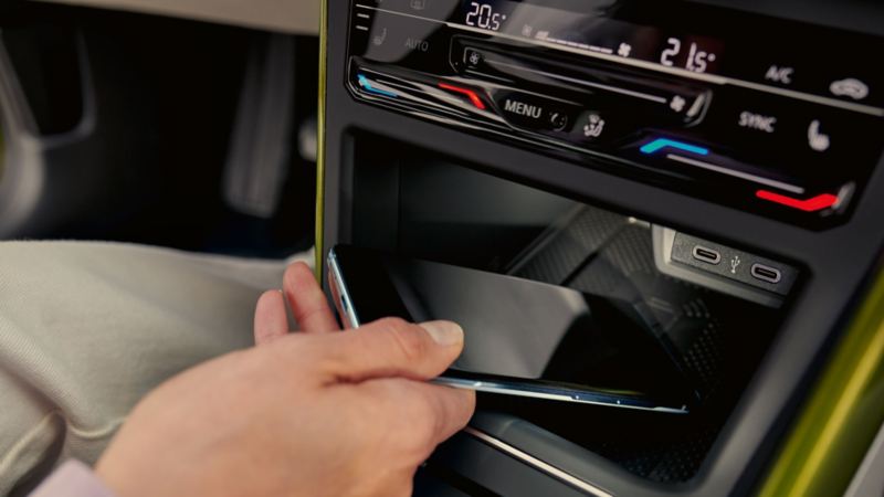 VW Taigo Interieur: Frau legt Smartphone in Ablagefach