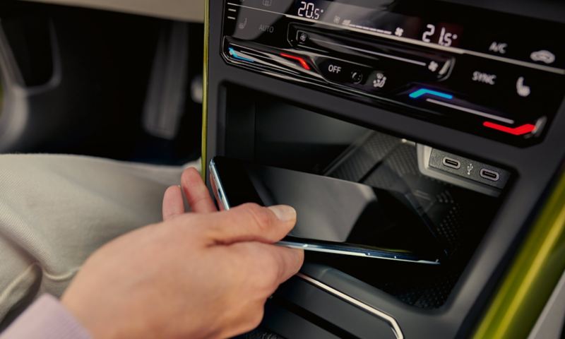 VW Taigo interior: A woman is placing a smartphone in the storage compartment