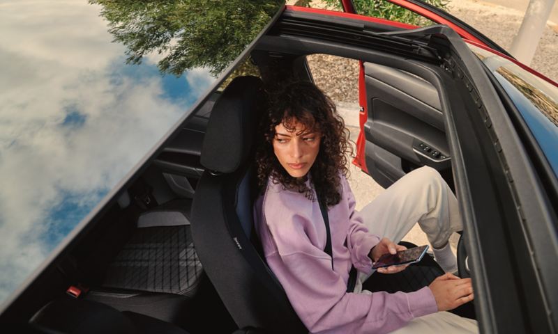 VW Taigo: View through optional tilting and sliding panoramic sunroof to a woman sitting in the driver seat