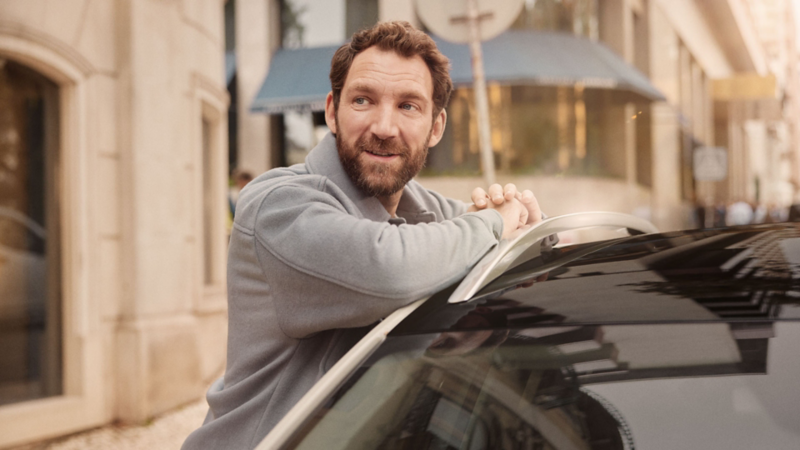 Un homme s’appuie sur le côté d’un Taigo Style avec toit noir.