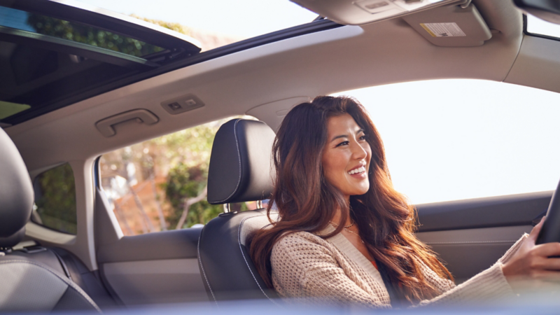 Une femme au volant d'un véhicule Volkswagen avec toit ouvrant