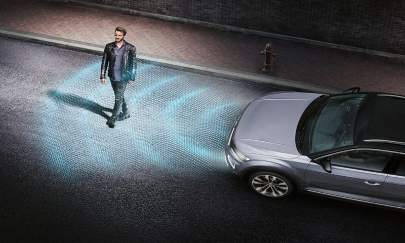 Man crossing street in front of T-Roc with graphic depiction of ‘Front Assist’ sensor system