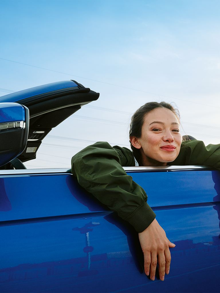 Frau im VW T-Roc Cabriolet und lächelt 