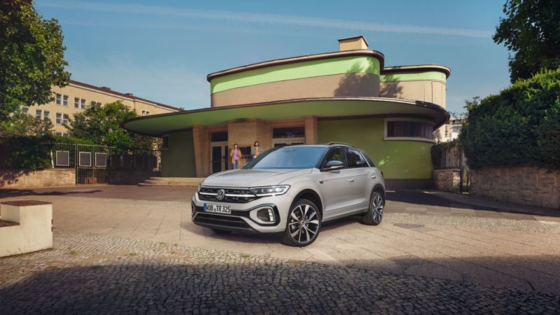 VW T-Roc R-Line en gris garée devant un bâtiment. Vue de face et de côté.