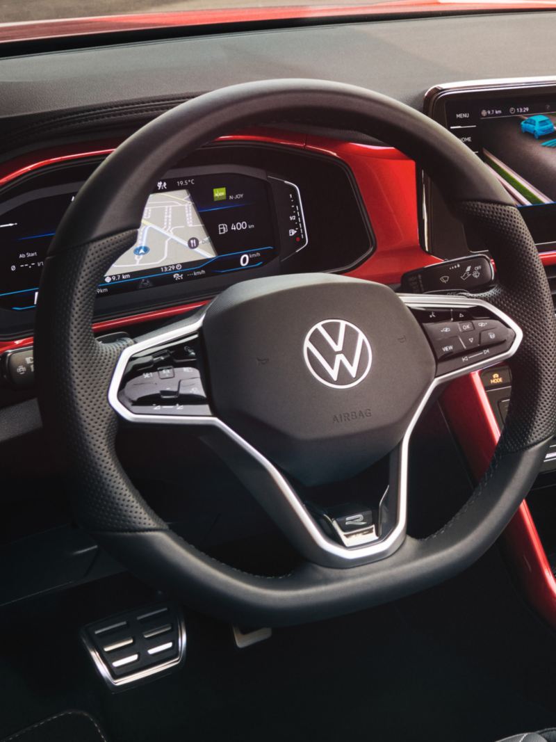 View of the cockpit of the red T-Roc Cabriolet with the multifunction steering wheel, radio and digital cockpit.