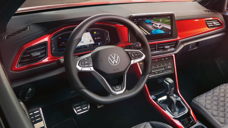 View of the cockpit of the red T-Roc Cabriolet with the multifunction steering wheel, radio and digital cockpit.
