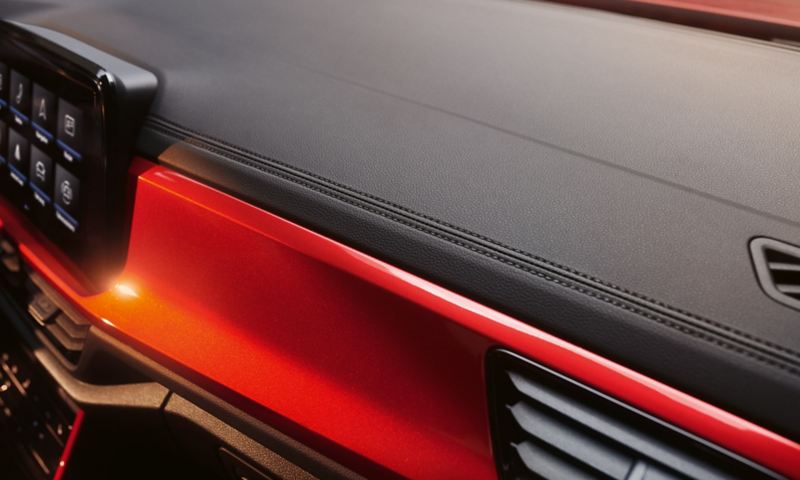 Λεπτομέρεια των διακοσμητικών ραφών στον πίνακα οργάνων του VW T-Roc Cabriolet με κόκκινο διάκοσμο.