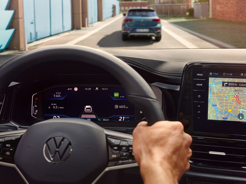 Dettaglio del volante multifunzione e del display di bordo da 8'', con funzione Travel Assist attiva, di Volkswagen Nuovo T-Roc.