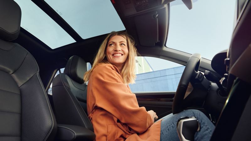 Eine Person sitzt auf dem Fahrersitz eines T-Roc und lächelt