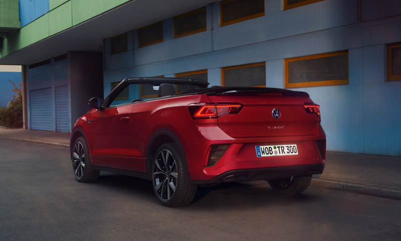 Ansicht des Hecks eines roten T-Roc Cabriolet mit geöffnetem Dach, parkend am Strassenrand. 