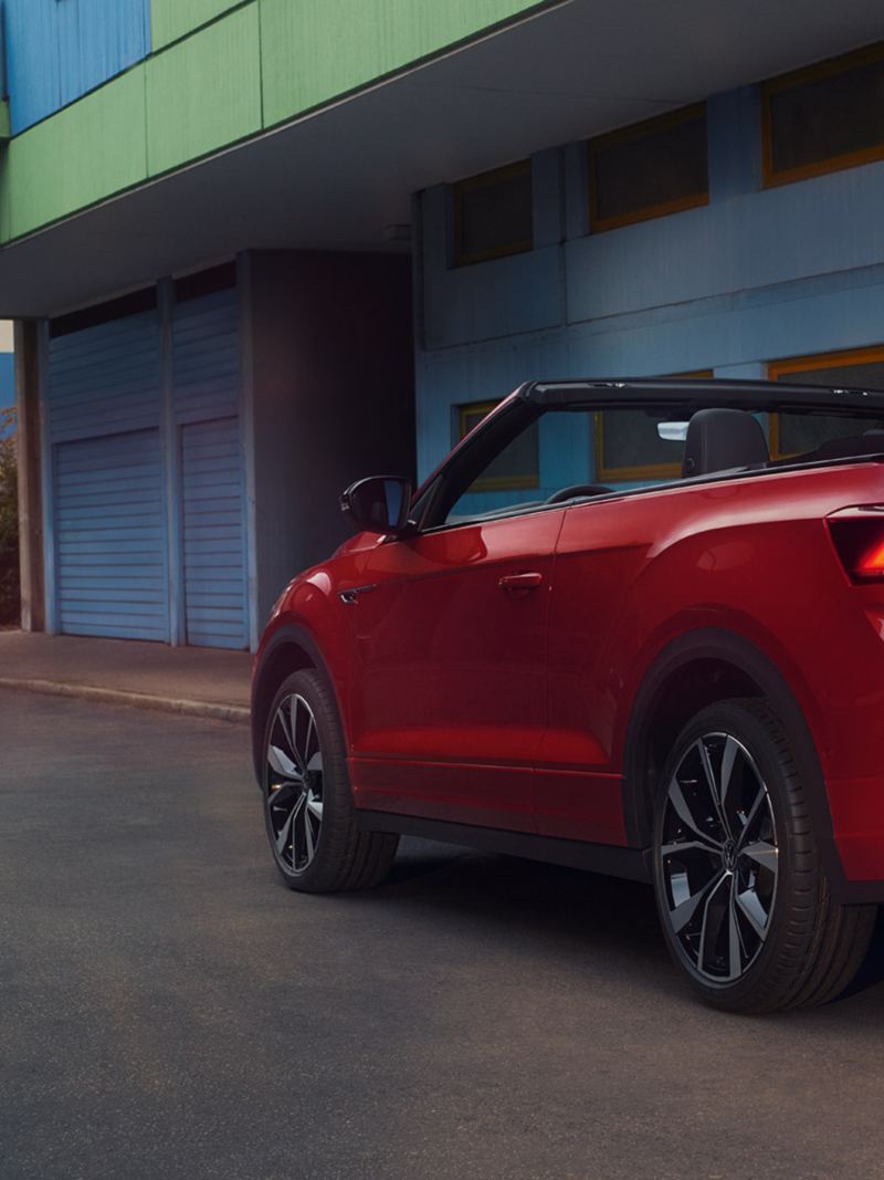 View of the rear of a red T-Roc Cabriolet with the roof open, parked on the side of the road.