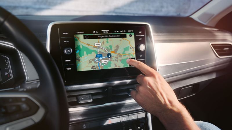 VW T-Roc Interieur, Detailansicht des Infotainment-Systems Discover Media, das gerade von einer Hand bedient wird