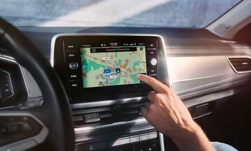 VW T-Roc Interieur, Detailansicht des Infotainment-Systems Discover Media, das gerade von einer Hand bedient wird