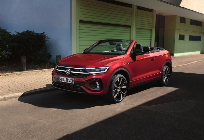 En rød VW T-Roc Cabriolet med åbent tag holder parkeret på en gade. 