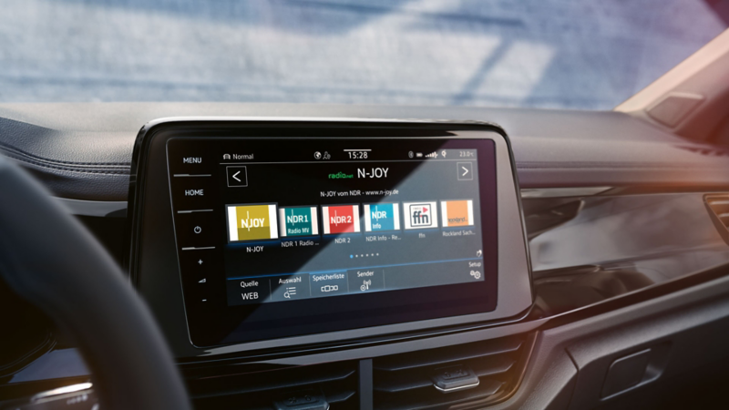 VW T-Roc Interieur, Detailansicht des Infotainment-Systems Discover Media, das gerade von einer Hand bedient wird
