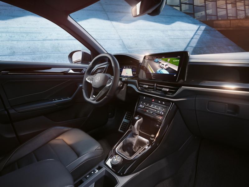  VW T-Roc interior, view from front passenger seat to driver’s seat and cockpit with multifunction steering wheel and infotainment system.