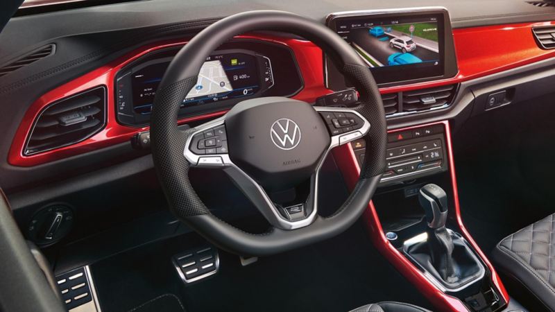 View of the cockpit of the red T-Roc Cabriolet with the multifunction steering wheel, radio and digital cockpit.