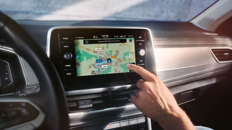 VW T-Roc Interieur, Detailansicht des Infotainment-Systems Discover Media, das gerade von einer Hand bedient wird