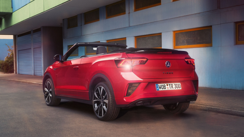 Ansicht des Hecks eines roten T-Roc Cabriolet mit geöffnetem Dach, parkend am Straßenrand.