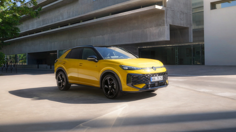 VW T-Roc jaune stationné de 3/4 avant devant un batiment.