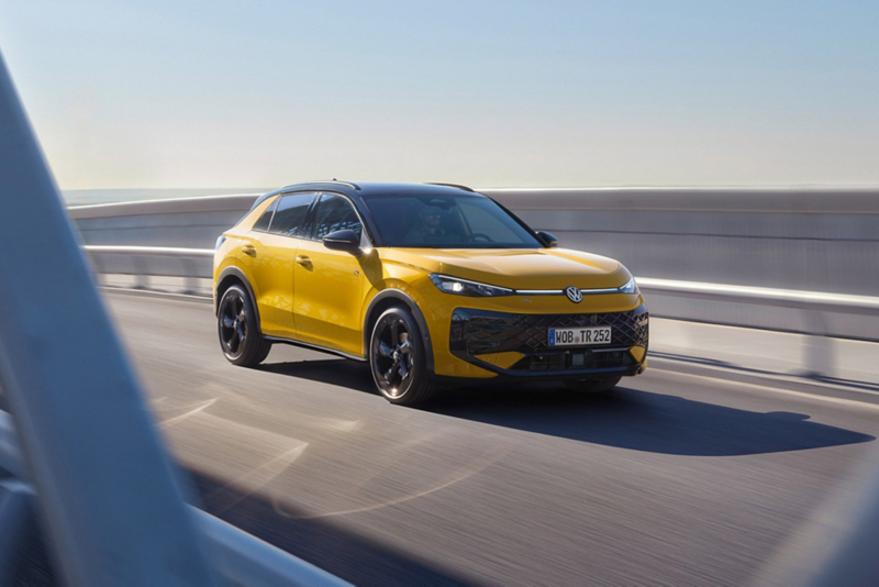 Three-quarter front view of a yellow Volkswagen T-Roc R-Line driving along a coastal road