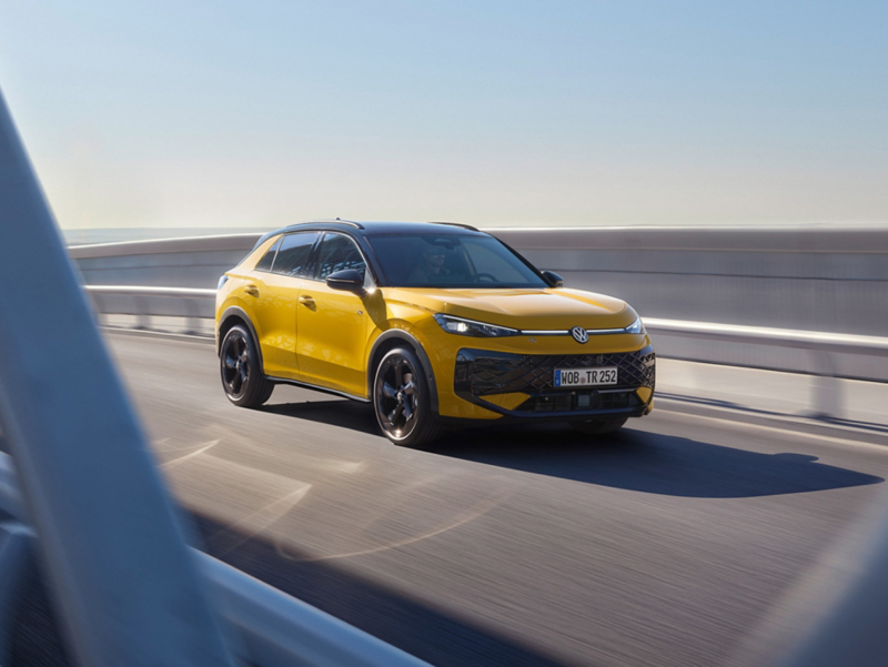 A yellow VW T-Roc driving across a bridge