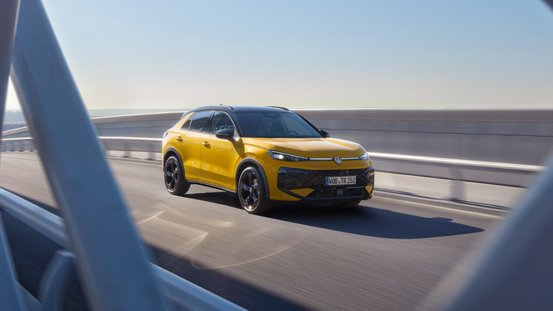 Un VW T-Roc R-Line jaune roulant sur un pont à structure métallique moderne.