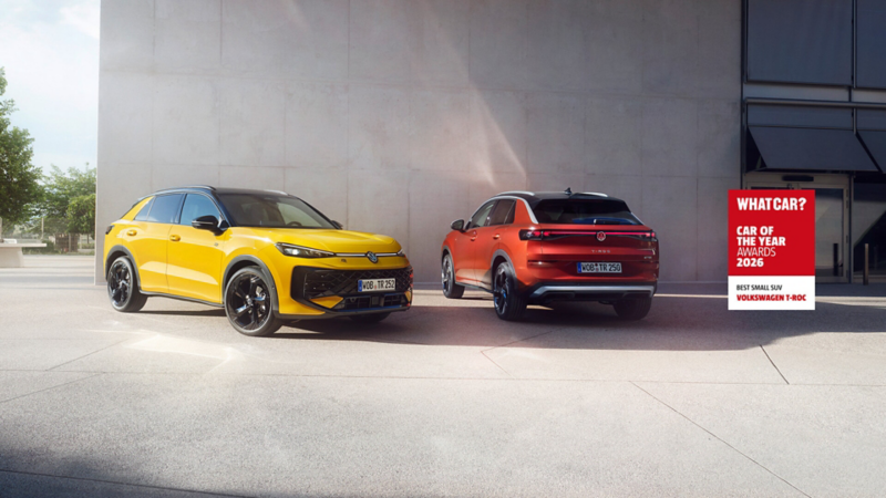 A yellow VW T-Roc R-Line and a red VW T-Roc Style next to each other in front of a concrete building. A red whatcar logo reads 'car of the year awards 2026, best small SUV Volkswagen T-Roc'
