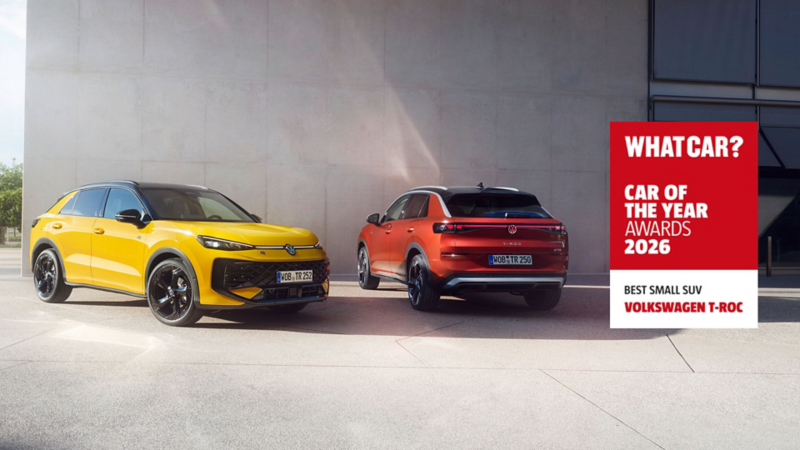 a yellow front facing T-Roc next to the back of a red T-Roc by a concrete building. A red whatcar logo sticker reads 'car of the year awards 2026, best small SUV Volkswagen T-Roc'