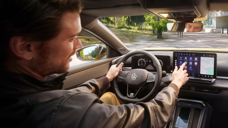 Ein Mann bedient auf dem Infotainment-Display in seinem Volkswagen T-Roc Android Auto über die App-Connect Schnittstelle.