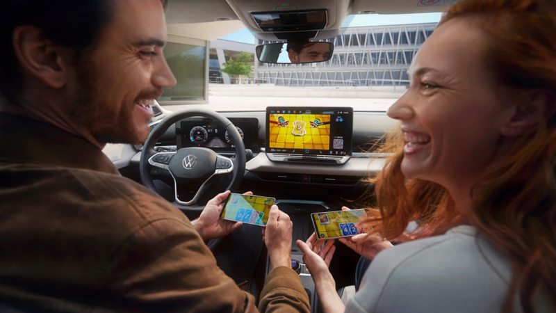 Un couple dans le T-Roc Style joue à Uno via AirConsole en utilisant des smartphones comme manettes.