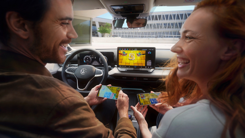 Un couple en T-Roc Style joue à Uno via AirConsole avec un smartphone comme contrôleur.