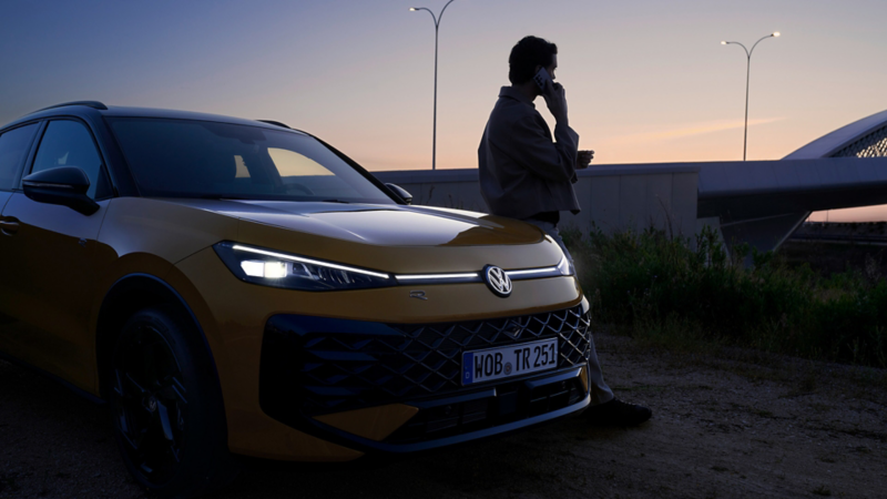 A woman walking away from a parked white VW T-Roc