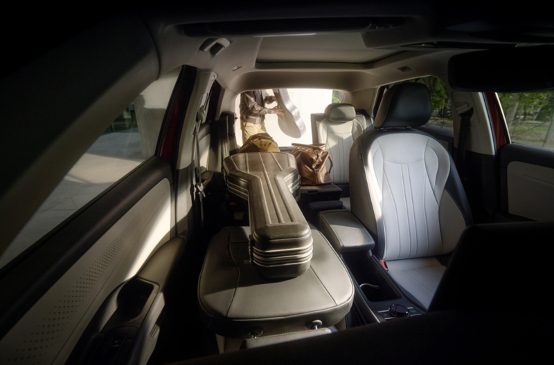 Interior del VW T-Roc Style con el asiento trasero y el asiento del pasajero delantero completamente abatidos, en los que descansa un estuche de guitarra.