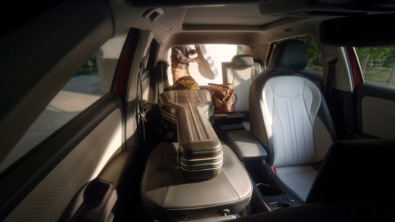 VW T-Roc Style interior with folded down rear bench seat and fully folded down front passenger seat on which a guitar case is lying.