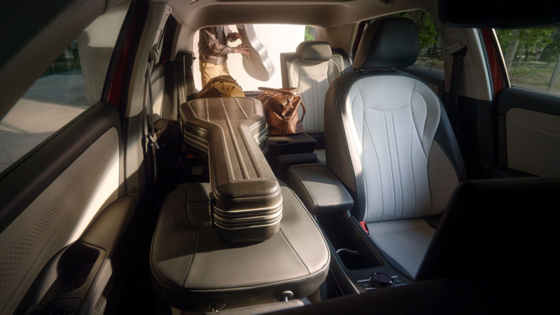 VW T-Roc Innenraum mit umgeklappter Rückbank und vollständig umgeklapptem Beifahrersitz, auf denen ein Gitarrenkoffer liegt.