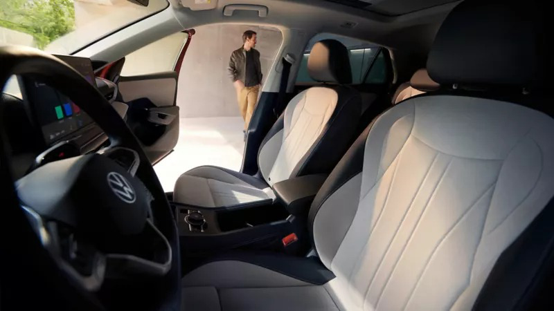 Widok przez drzwi kierowcy na wnętrze VW T-Roc Style z jasnymi siedzeniami