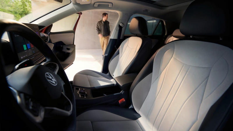 Vue à travers la porte conducteur du VW T-Roc Style sur l’intérieur avec des sièges de couleur claire.